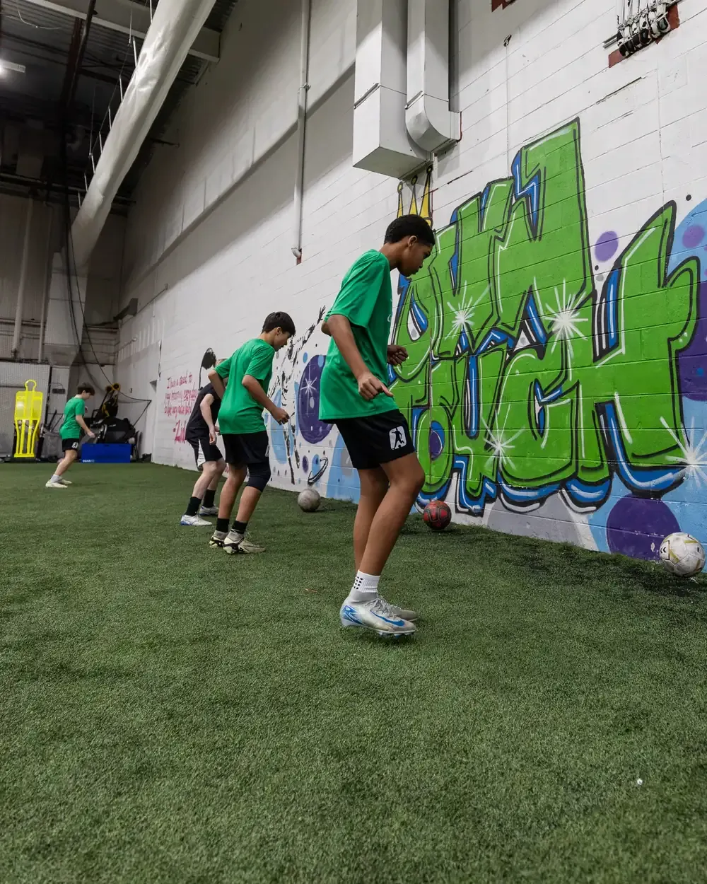 Players working through a footwork pattern along the Own Touch mural wall