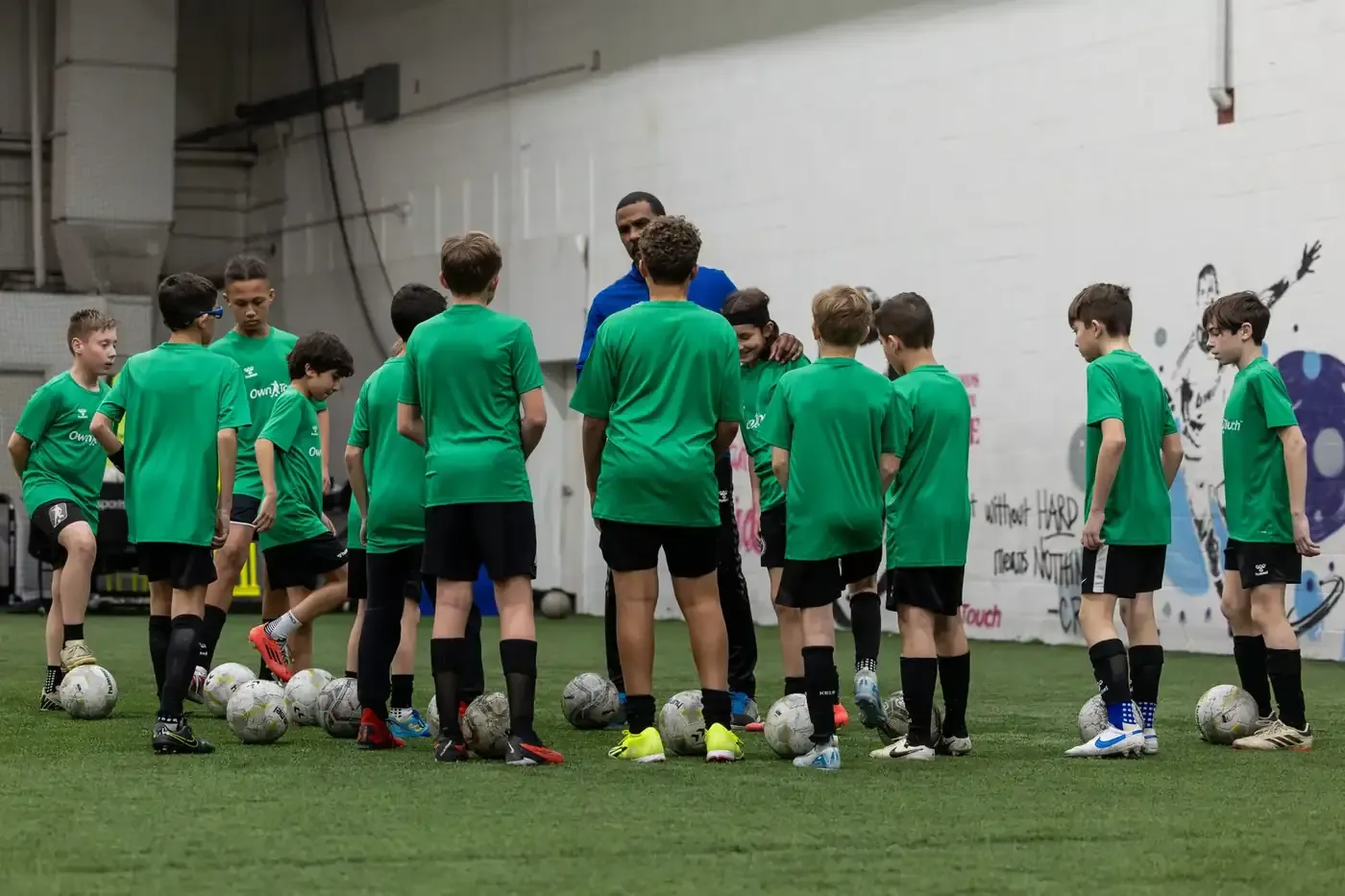 A coach talking through the next exercise with a huddle of campers