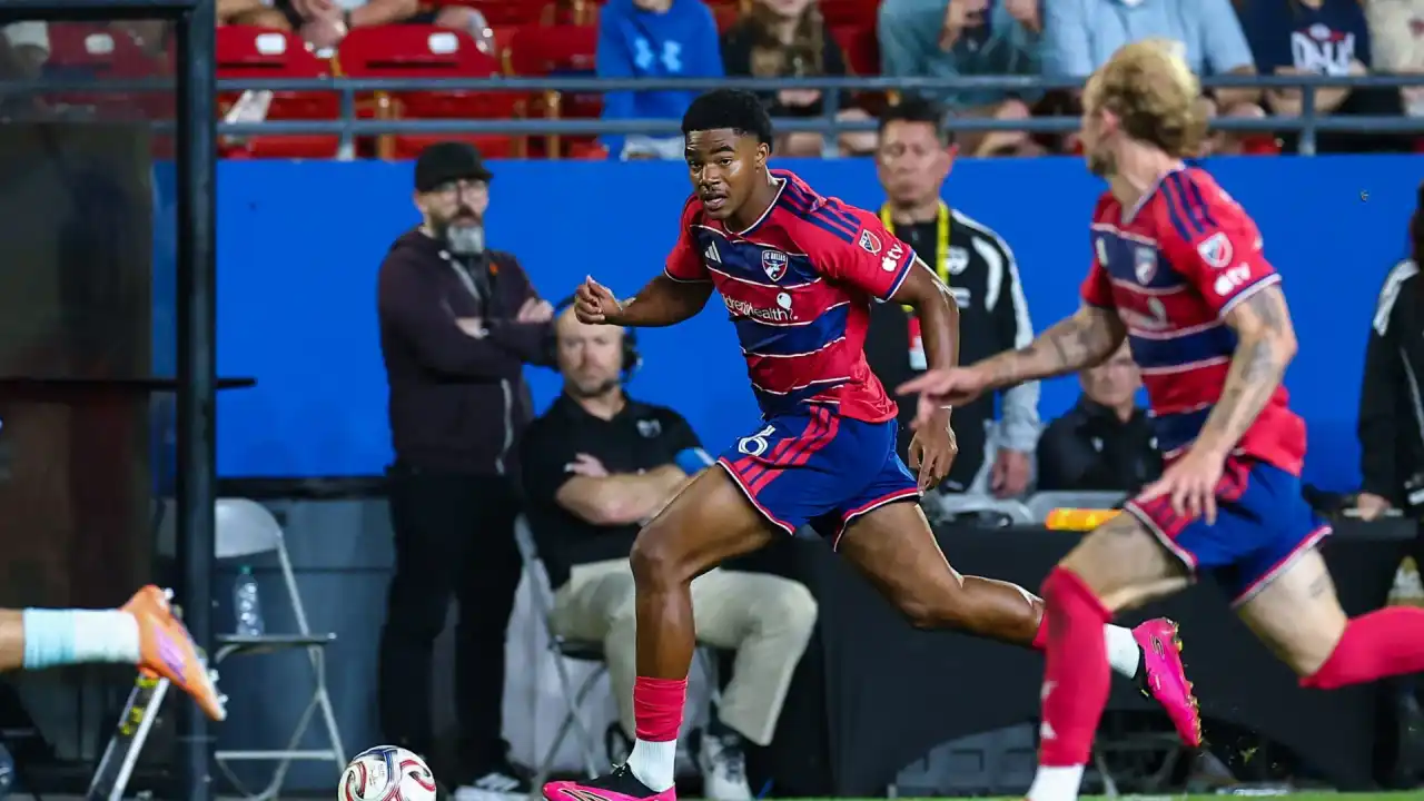 A player in a red and blue hooped kit driving forward with the ball during a professional match