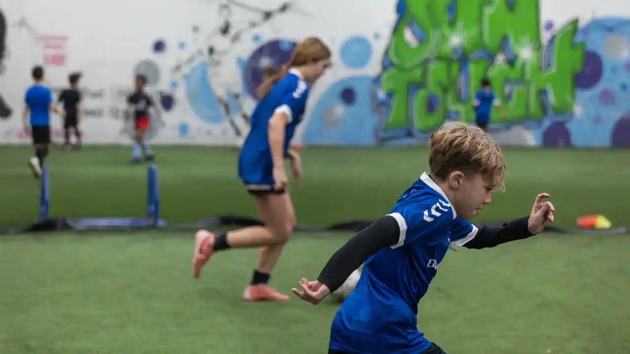 Young players running drills on the indoor pitch at Own Touch Soccer, Charlotte