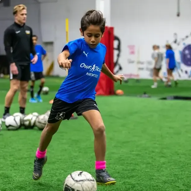 Mentee players lined up on the indoor pitch during a training session