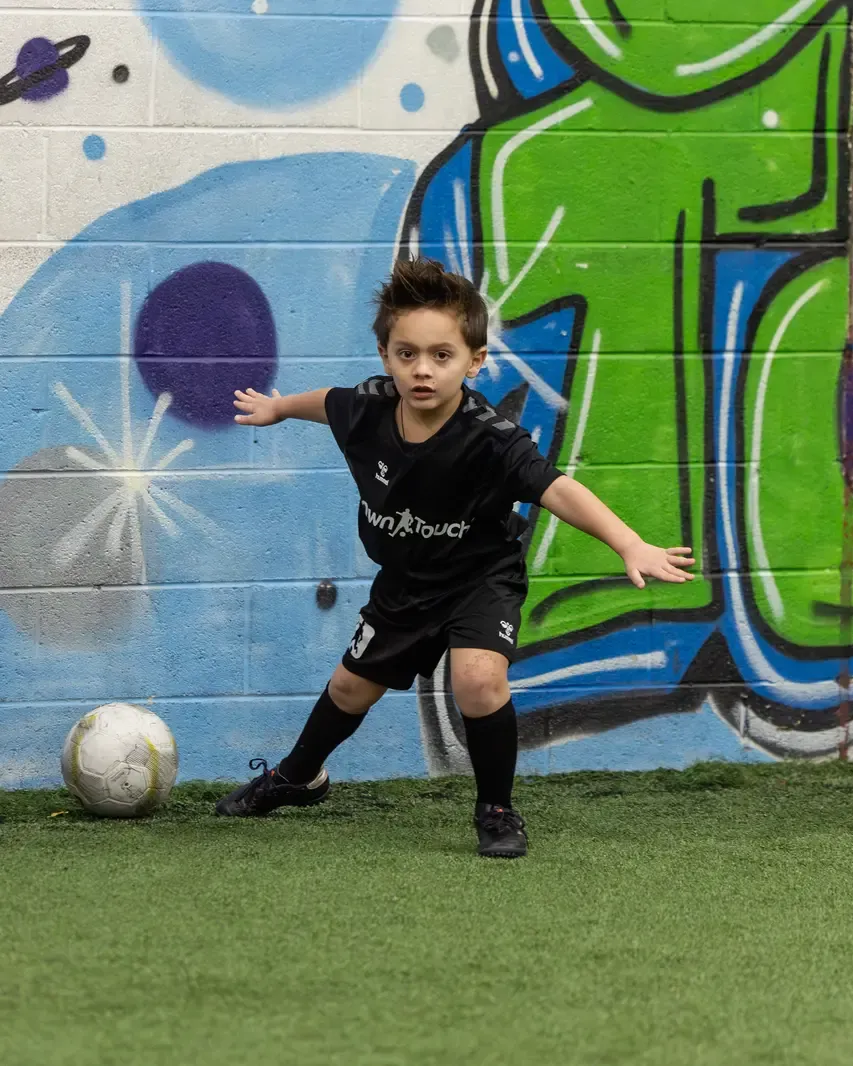 A young player moving with the ball during a Mini Mentee session