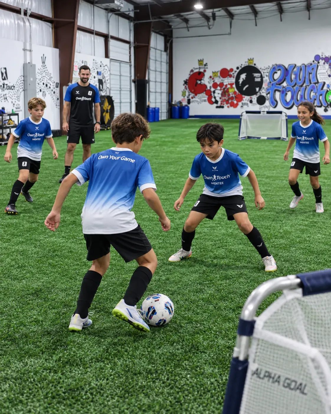 Mentees in blue Own Touch kits working the ball as a coach watches