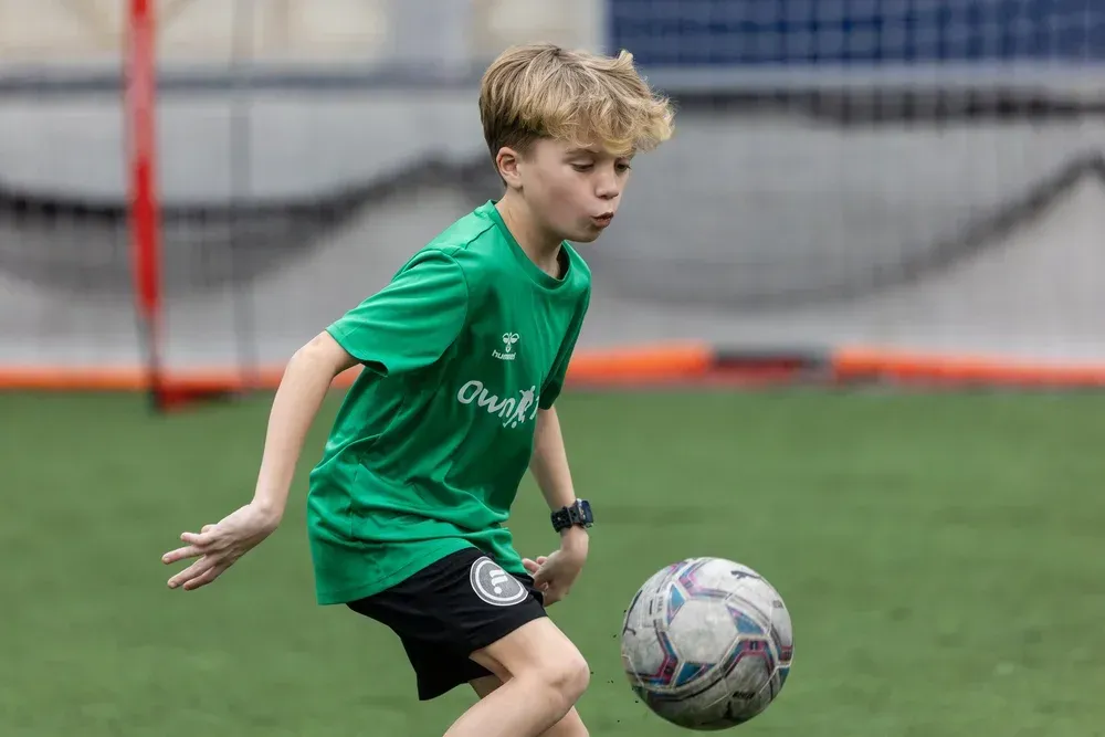 A Prospect in a green Own Touch shirt reading a bouncing ball