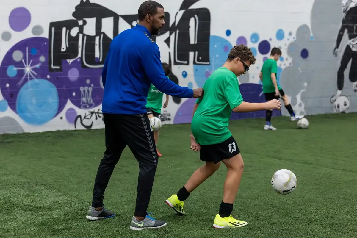 Coach working one-on-one with a player on the indoor pitch